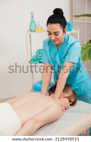massage therapist does a therapeutic back massage for a woman in the spa