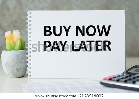 On a white table is a calculator and a notepad with the inscription BUY NOW PAY LATER.
