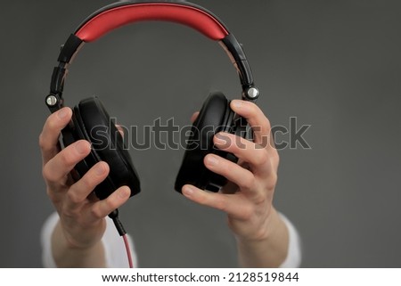 hand with headphones listening to music with grey background stock photo 