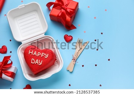 Composition with tasty bento cake and gifts on blue background