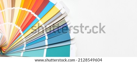 Color guide close up. Assortment of colors for design. Colors palette fan on white concrete wall background. Graphic designer chooses colors from the color palette guide. Coloured swatches catalogue