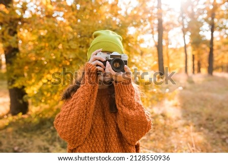 Young woman taking picture in autumn forest