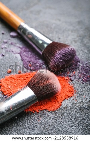 Makeup brushes and loose eye shadow on dark background