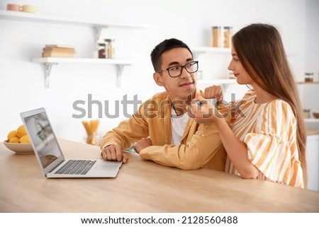 Young couple using laptop at table in kitchen