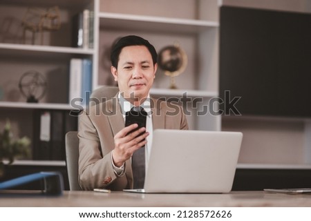 Young businessman in a suit. Use your mobile smartphone and tablet to communicate with customers, online business, online meetings. Royalty-Free Stock Photo #2128572626