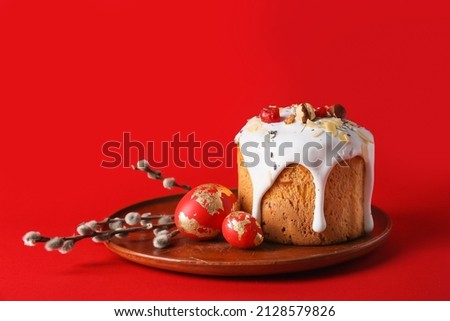 Plate with delicious Easter cake, eggs and pussy willow branches on red background Royalty-Free Stock Photo #2128579826