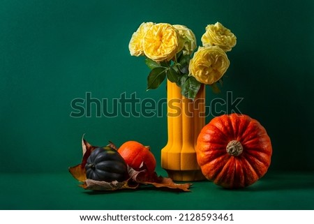 still life on a green background with pumpkins and yellow English roses