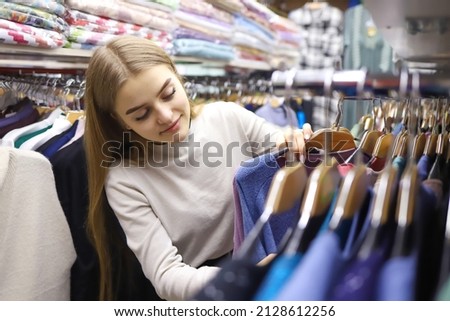 Pretty young woman with long hair chooses clothes in a store. concept of shopping, fashion, sales