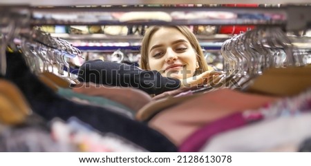 Pretty young woman with long hair chooses clothes, jeans in a store. shopping, fashion, sales concept