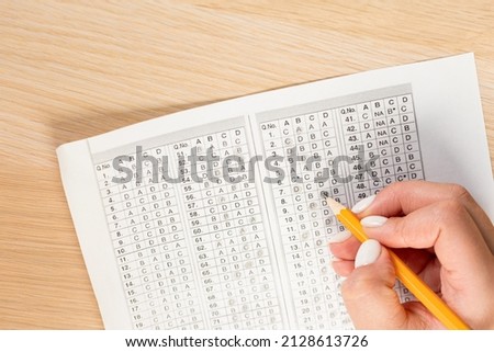 Students hands to take exams, writing an exam room with a pencil holding on an optical form of a standardized test with answers 