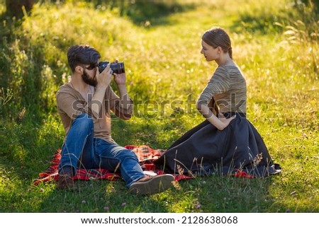 the guy photographs his girlfriend with a camera in a summer park