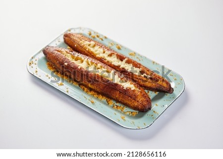 Ecuadorian maduro con queso consists of baked ripe plantains stuffed with cheese. It’s on a white background.  Royalty-Free Stock Photo #2128656116