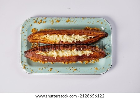 Ecuadorian maduro con queso consists of baked ripe plantains stuffed with cheese. It’s on a white background.  Royalty-Free Stock Photo #2128656122