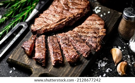 Sliced grilled steak on a cutting board. On a black background. High quality photo