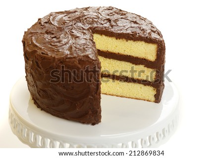 Yellow layer cake with chocolate icing with one slice missing. Royalty-Free Stock Photo #212869834