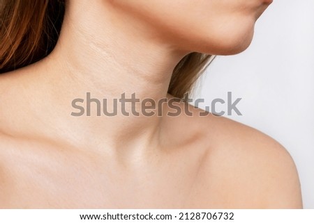 Сropped shot of a young woman with lines on the neck isolated on a white background. Wrinkles, creases, age-related changes, rings of Venus. Skin care Royalty-Free Stock Photo #2128706732