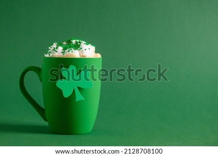 Irish coffee in green cup with whipped cream and sprinkles for St Patricks Day on green background. Close up. Copy space. Happy st Patricks day.