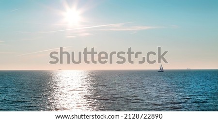 View of the sea, the ocean with a sailboat on the horizon and the bright sun and a sunny path on a clear day. Landscape travel landscape sights of Europe. Royalty-Free Stock Photo #2128722890