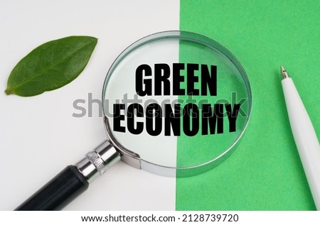 Ecological concept. On a white-green background lies a pen, a leaf of a plant and a magnifying glass, inside which is the inscription - Green economy