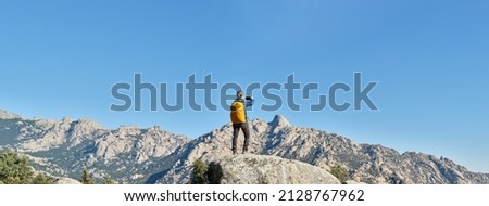 A woman hiker taking a picture of the landscape with her smart phone