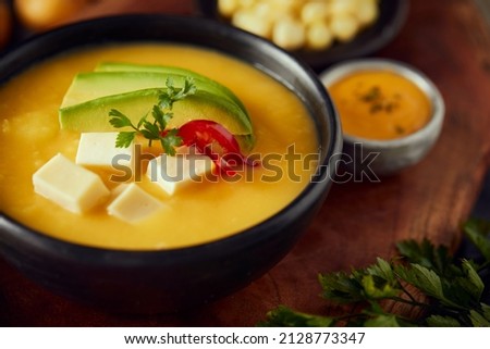 Ecuadorian locro de papa a traditional potato and cheese soup served with avocado and hominy. It’s on a wooden background Royalty-Free Stock Photo #2128773347