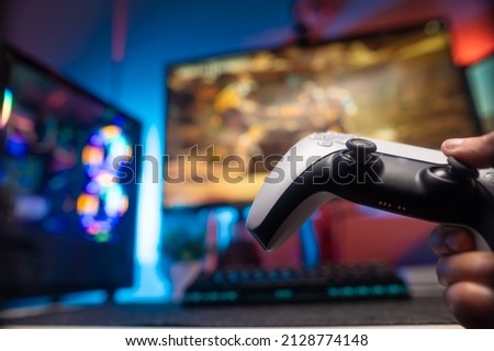 Gamepad, personal computer, big screen TV. Neon lighting. Video games, game strategy, esports, cyberspace, virtual reality. There are no people in the photo.