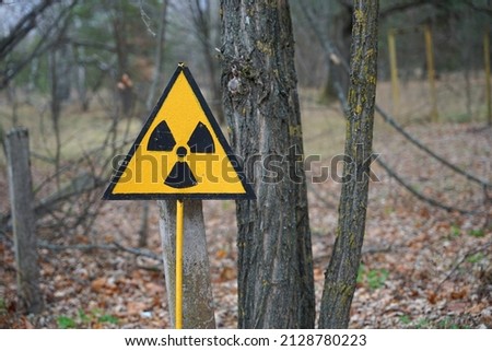 Nuclear radioactive danger sign in forest in Chernobyl exclusion zone around Chornobyl Nuclear Power Station Royalty-Free Stock Photo #2128780223