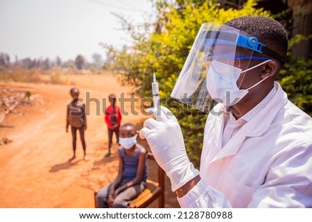 An African doctor is about to vaccinate children to prevent coronavirus infection. Vaccination concept in africa Royalty-Free Stock Photo #2128780988