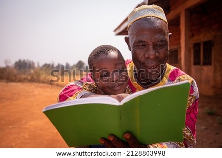 African grandfather reads a book with his grandson, moment of love and tenderness between them. Concept of grandfather educating his grandson Royalty-Free Stock Photo #2128803998