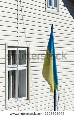 Flag of Ukraine near the window of the house in the yard. Side view