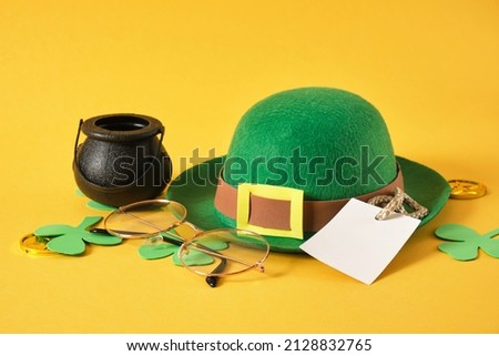 blank tag, glasses, coins, leprechaun hat and clover leaves on yellow background, st. patrick's day concept, save space