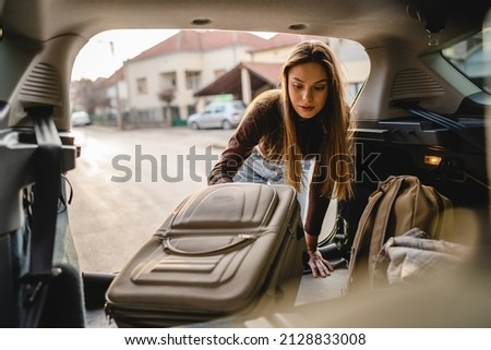 One young beautiful woman student travel concept female take luggage baggage suitcase and other stuff and belongings from the back of her car while moving into dormitory on college campus real people Royalty-Free Stock Photo #2128833008