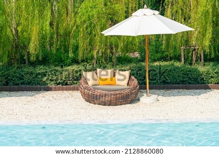 outdoor patio chair with pillow and umbrella around swimming pool - holidays and vacation concept