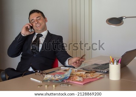 businessman in office talking on the phone while holding banknotes in hand making fortune in finance	