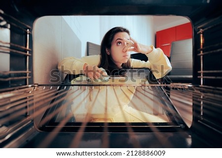 Unhappy Woman Cleaning Stinky Dirty Oven with a Rag. Young girl doing unpleasant domestic chores wiping dirty smelly stove Royalty-Free Stock Photo #2128886009