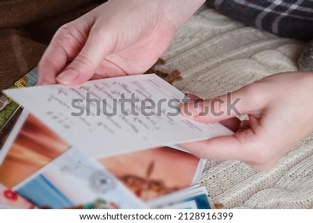 Woman read old post cards sitting on sofa, hands close up Royalty-Free Stock Photo #2128916399