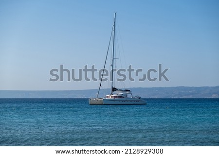 Sailing boat catamaran anchored at rippled sea, Land and blue sky background. Summer vacation