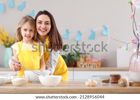 Little girl with her mother preparing dough for Easter cake in kitchen Royalty-Free Stock Photo #2128956044