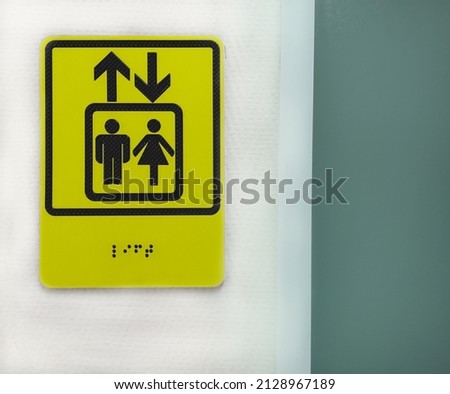 Elevator sign in Braille in hospital. Sign for blind people, vision problem, health problems. Elevator sign for people with disabilities. Elevator buttons, up and down arrows.