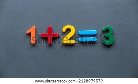 One plus two equal to three. Colorful numbers on a grey background.