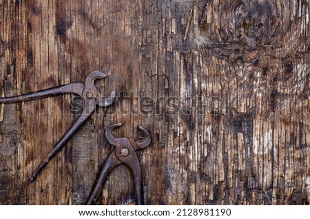 Hand Tools. Old, rusty pincers on Dark Wooden Background. Cracked wooden surface with cracks and splinters. Selective focus.