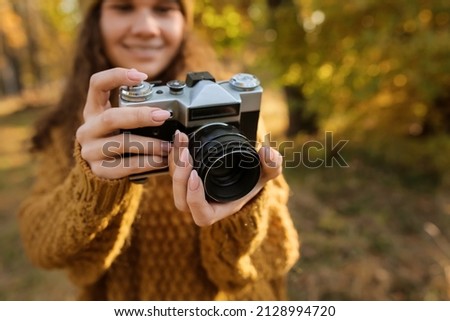Female photographer with photo camera in autumn forest