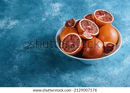 plate with red oranges on blue background, citrus fresh mood