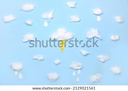 Clouds made of cotton wool and paper lightning on color background Royalty-Free Stock Photo #2129021561