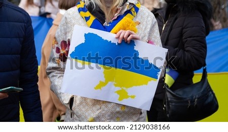 Outline of Ukraine. Protester holding a sign with Ukrainian flag map. Demonstration against a war and Russia invasion on Ukraine. Russian attack protest, manifestation. Royalty-Free Stock Photo #2129038166