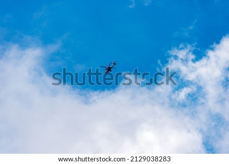 Italian military helicopter in motion against a clear blue sky with clouds, Italian Alps, Trentino-Alto Adige, Italy, Europe.