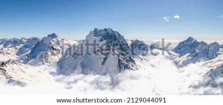 Snowy slope of high mountains above the clouds Royalty-Free Stock Photo #2129044091