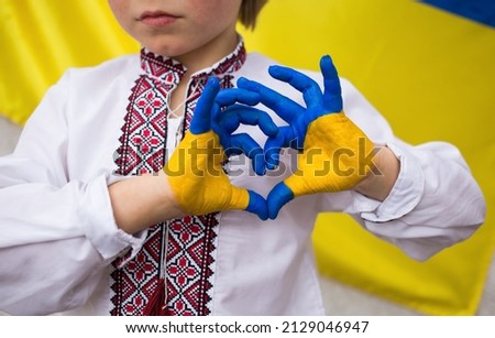 Children against war. Russia's invasion of Ukraine, request for help from world community. child against background of Ukrainian flag with hands in shape of a heart, painted in yellow and blue Royalty-Free Stock Photo #2129046947