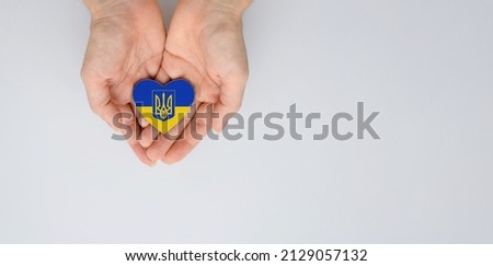 The national flag of ukraine with the coat of arms in female hands. Flat lay, copy space. Royalty-Free Stock Photo #2129057132