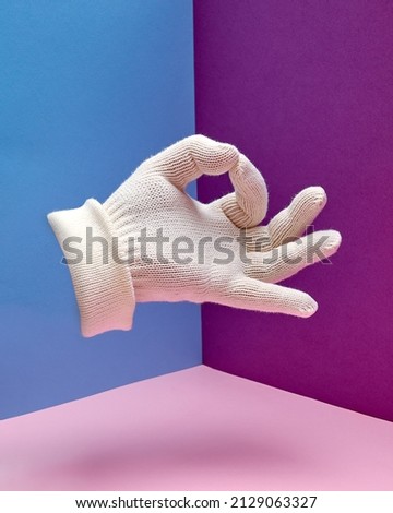 A hand in a white glove shows a sign zero or okay. Hand gesture.